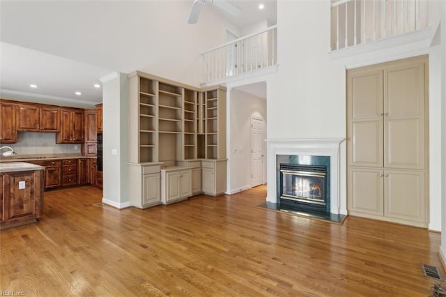 kitchen with ceiling fan, visible vents, a premium fireplace, and light wood-style flooring