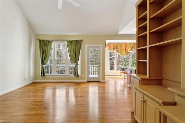 unfurnished living room with a healthy amount of sunlight, baseboards, lofted ceiling, and light wood-style floors