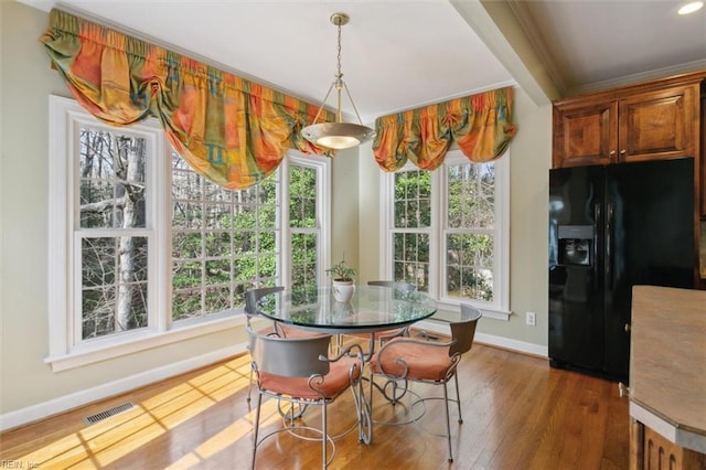 dining room with visible vents, baseboards, wood finished floors, and crown molding