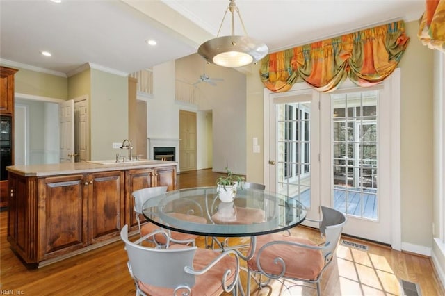 dining space with light wood-type flooring, visible vents, and a lit fireplace