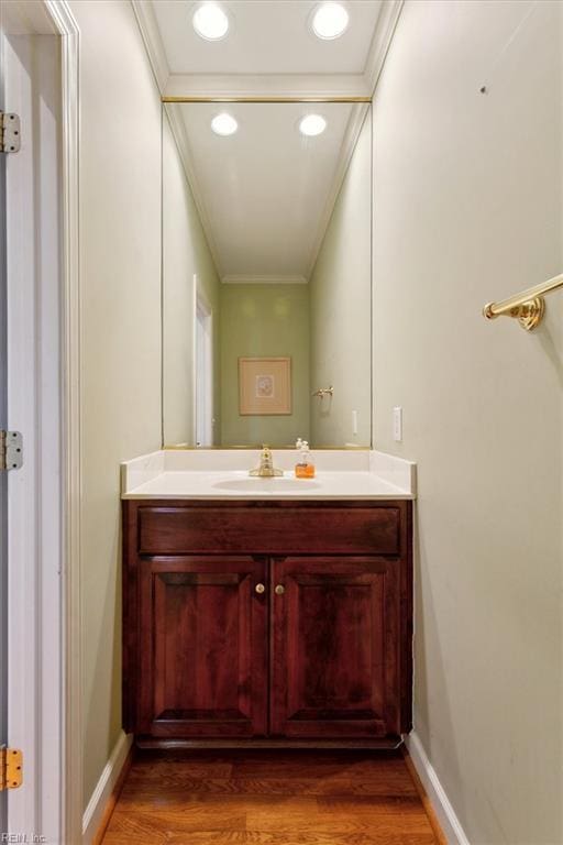 bathroom featuring vanity, wood finished floors, baseboards, and ornamental molding