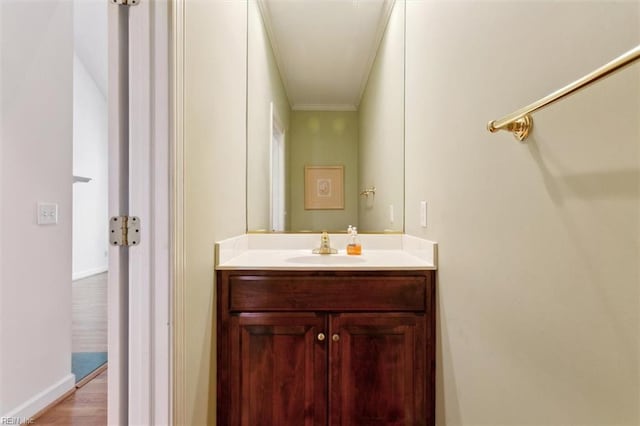 bathroom featuring vanity, crown molding, baseboards, and wood finished floors