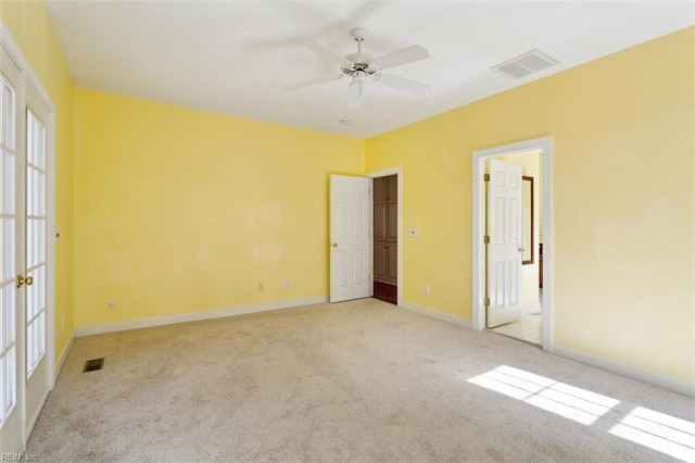 spare room featuring ceiling fan, light colored carpet, visible vents, and baseboards