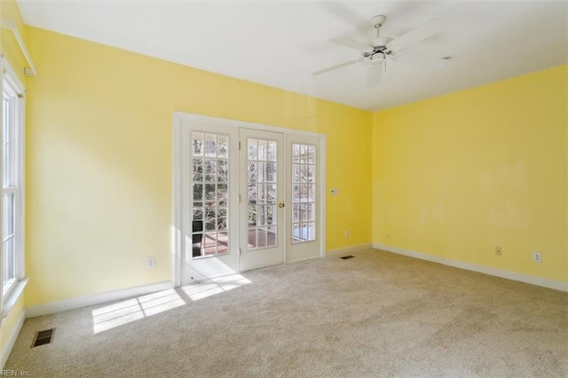 empty room with carpet flooring, ceiling fan, baseboards, and visible vents