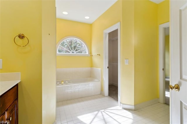 bathroom featuring tile patterned flooring, baseboards, vanity, and a garden tub