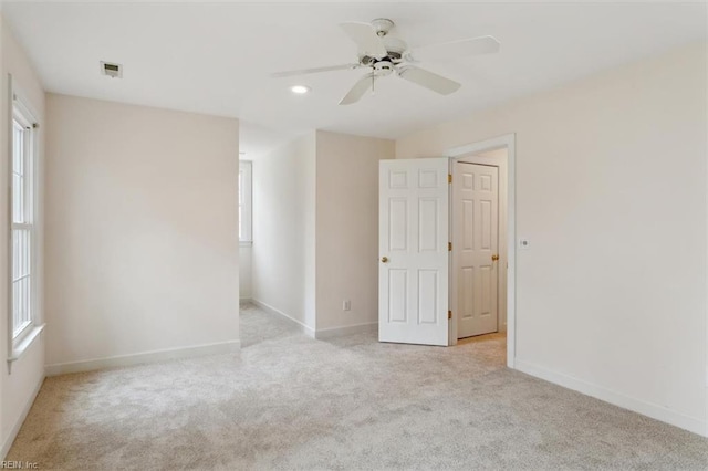 unfurnished room with plenty of natural light, visible vents, baseboards, and light carpet