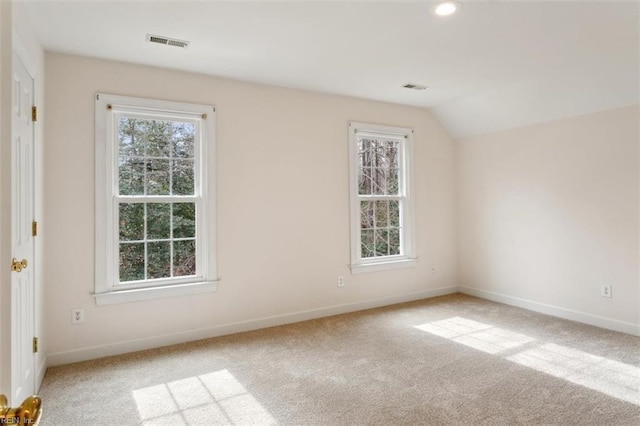 carpeted empty room featuring visible vents, baseboards, and vaulted ceiling