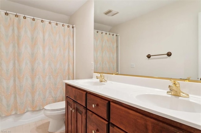 full bath with a sink, toilet, double vanity, and tile patterned flooring