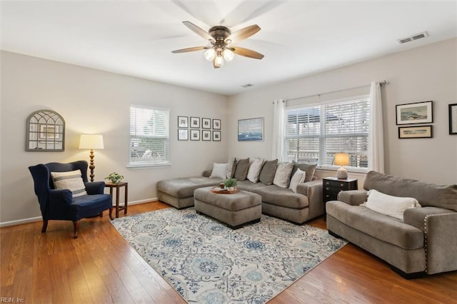 living area with visible vents, baseboards, a ceiling fan, and wood finished floors