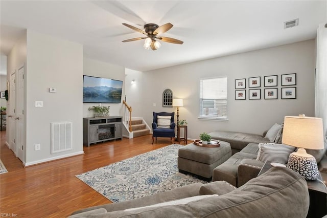 living area with baseboards, wood finished floors, visible vents, and ceiling fan