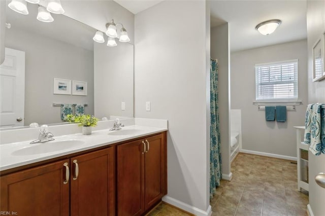 full bath with tile patterned flooring, double vanity, baseboards, and a sink