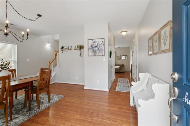 dining room with visible vents, baseboards, stairway, light wood-type flooring, and a notable chandelier