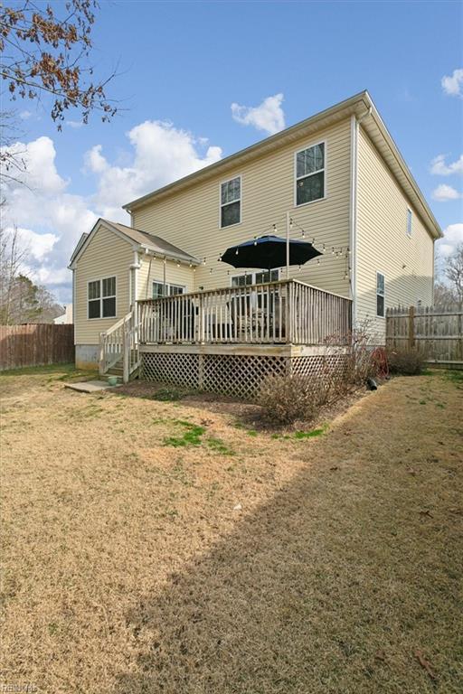 rear view of property with a deck, fence, and a lawn