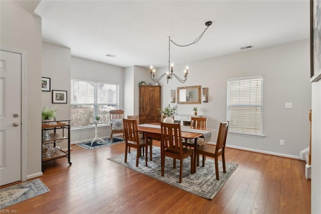 dining room featuring visible vents, baseboards, a notable chandelier, and hardwood / wood-style floors