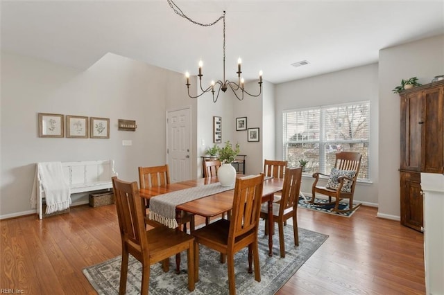 dining area with visible vents, an inviting chandelier, baseboards, and wood finished floors