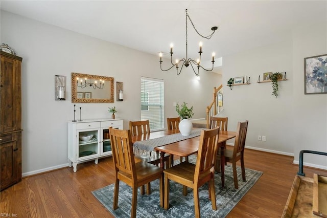 dining space featuring an inviting chandelier, stairway, wood finished floors, and baseboards