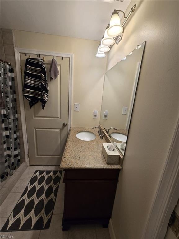 full bath featuring a shower with shower curtain, double vanity, tile patterned floors, and a sink