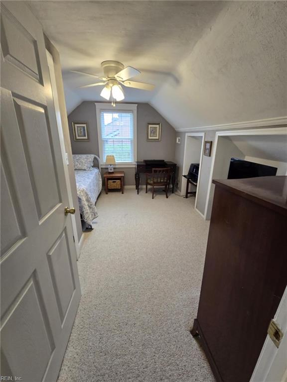 carpeted bedroom with lofted ceiling, a textured ceiling, and ceiling fan