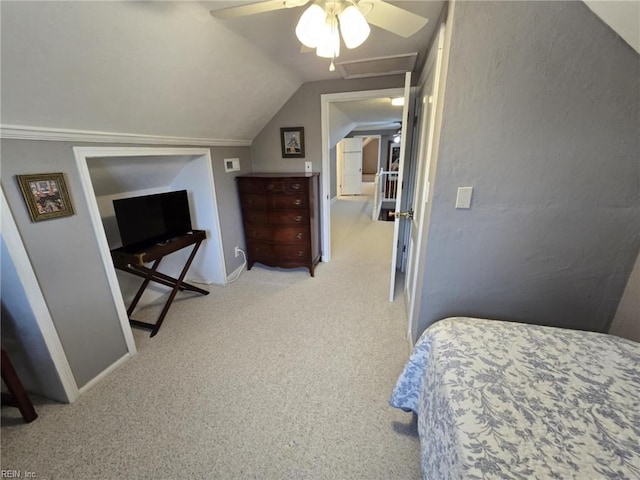 bedroom with a ceiling fan, carpet floors, baseboards, attic access, and vaulted ceiling