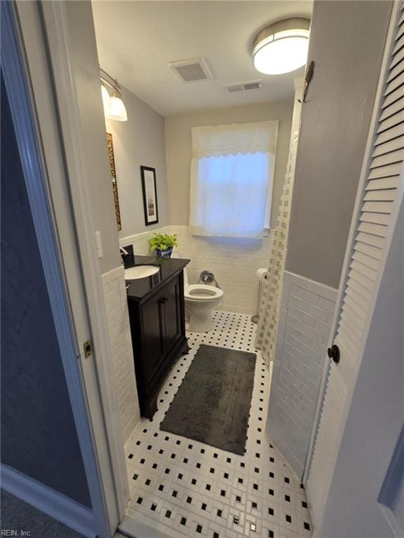 bathroom featuring tile patterned floors, visible vents, toilet, wainscoting, and vanity