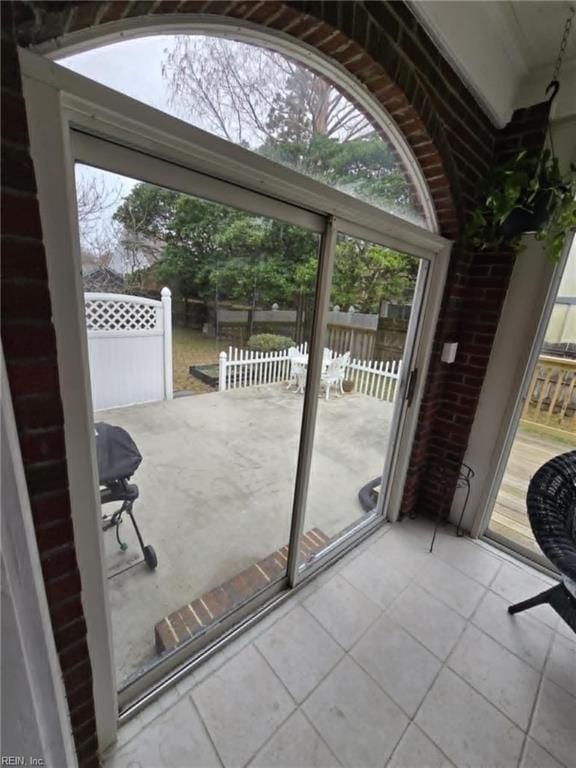 doorway to outside with tile patterned flooring and brick wall