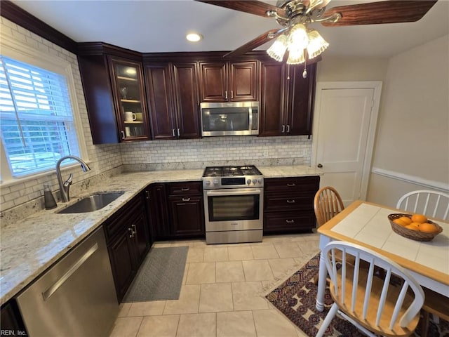 kitchen featuring a sink, decorative backsplash, light stone countertops, and stainless steel appliances