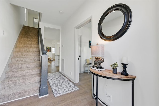 foyer entrance with stairway, baseboards, and wood finished floors