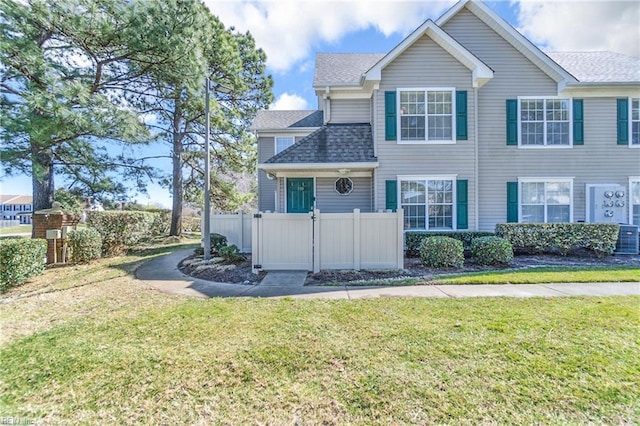 view of front of house featuring a front yard, fence, and roof with shingles