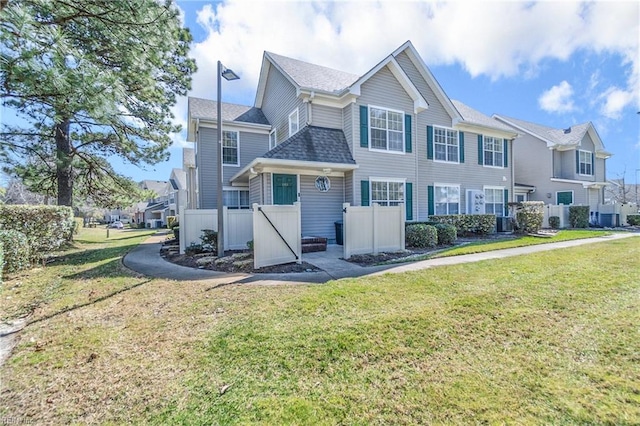 view of front of home featuring roof with shingles, a front yard, and fence