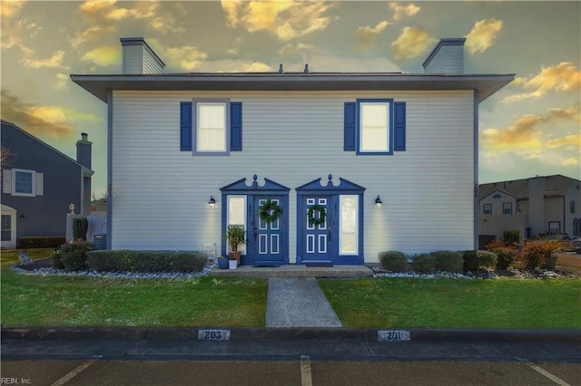 view of front facade with a chimney and a yard