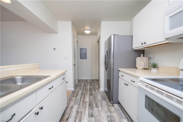 kitchen with light wood-style flooring, a sink, white cabinetry, white appliances, and light countertops