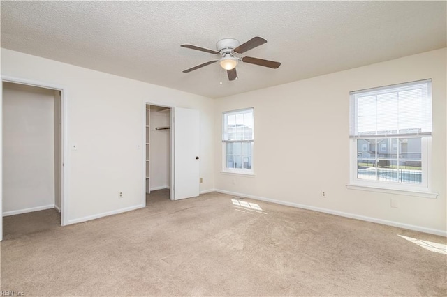 unfurnished bedroom featuring baseboards, multiple windows, a textured ceiling, and carpet flooring