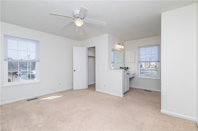 unfurnished bedroom featuring multiple windows, visible vents, and light carpet