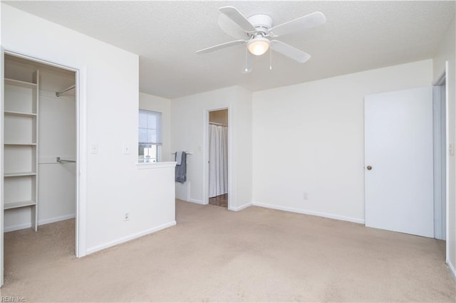 unfurnished bedroom with a spacious closet, a closet, a textured ceiling, and carpet