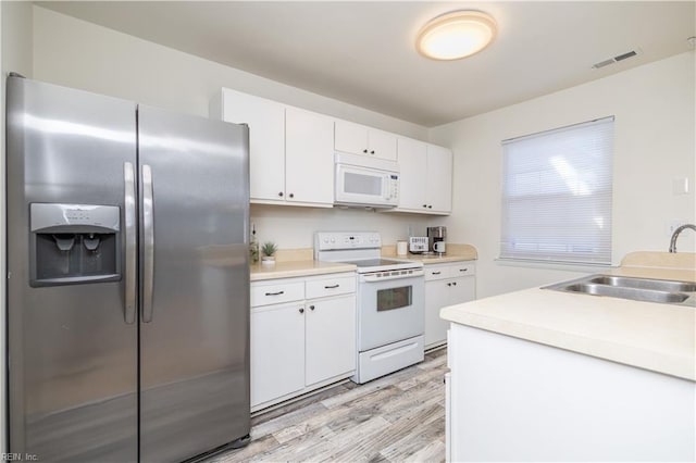 kitchen featuring white appliances, visible vents, light wood-style flooring, a sink, and white cabinets