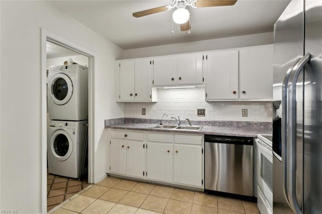 kitchen featuring a sink, stainless steel appliances, decorative backsplash, and stacked washer / dryer