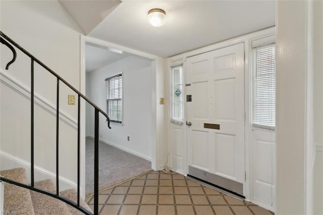 foyer with stairs, light floors, and baseboards