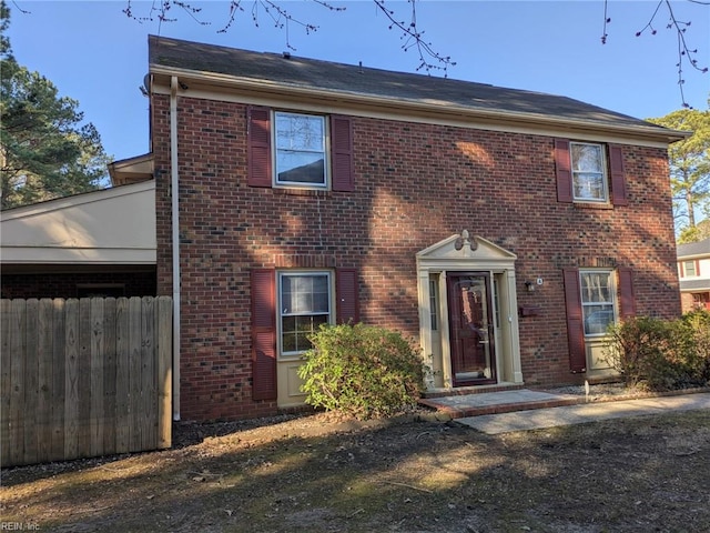 colonial inspired home with fence and brick siding