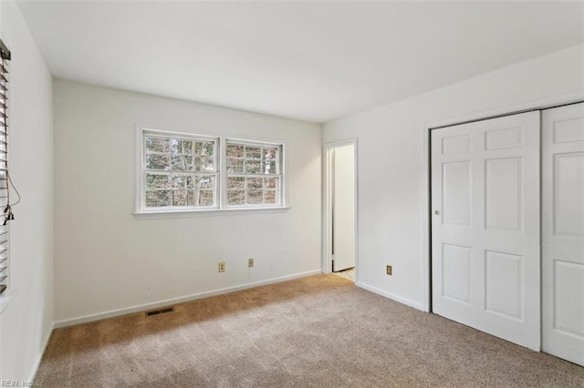 unfurnished bedroom featuring baseboards, visible vents, carpet floors, and a closet