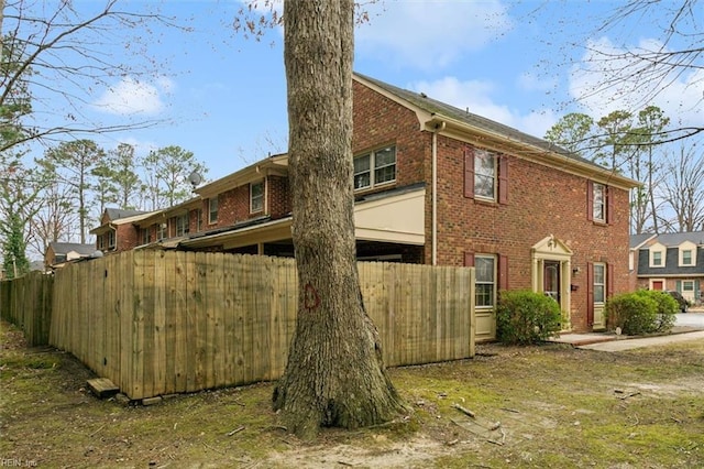 view of side of property featuring fence and brick siding