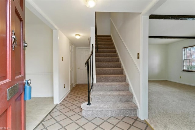 foyer entrance with stairway, light carpet, and baseboards