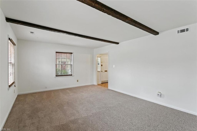 unfurnished room with visible vents, baseboards, beamed ceiling, and carpet flooring