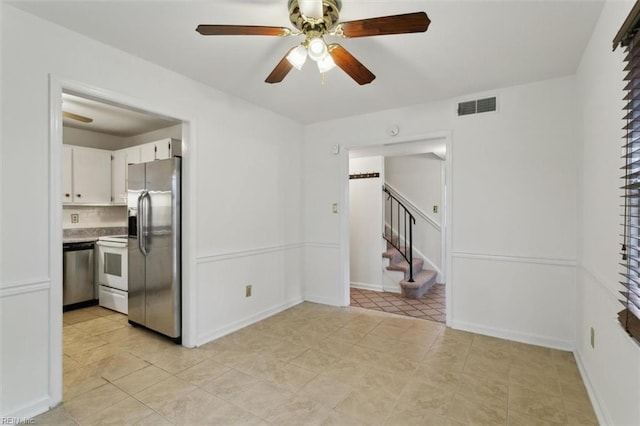 interior space featuring a ceiling fan, visible vents, light countertops, appliances with stainless steel finishes, and white cabinetry