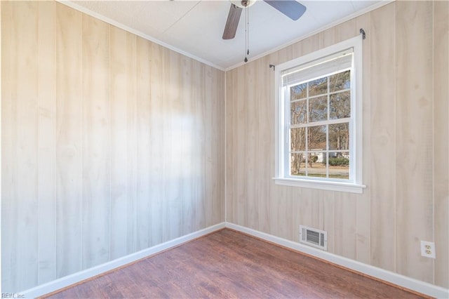 unfurnished room featuring visible vents, ceiling fan, baseboards, ornamental molding, and wood finished floors