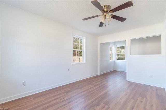 spare room with baseboards, a textured ceiling, ceiling fan, and wood finished floors