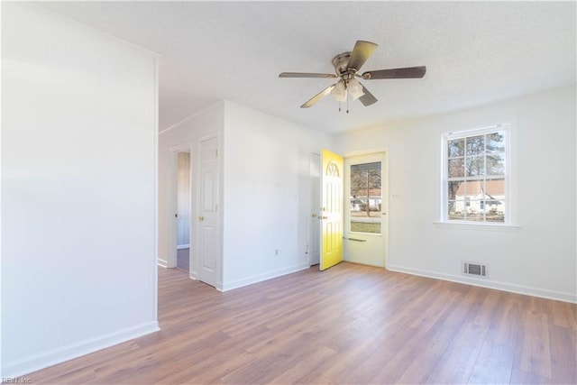 unfurnished room with visible vents, a ceiling fan, a textured ceiling, wood finished floors, and baseboards