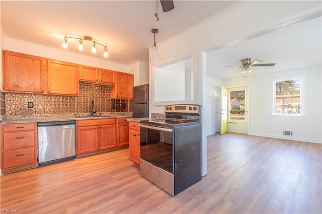 kitchen with a sink, decorative backsplash, light wood-type flooring, and appliances with stainless steel finishes