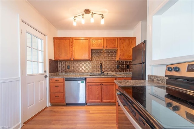 kitchen featuring a sink, stainless steel appliances, light wood-style floors, brown cabinetry, and crown molding