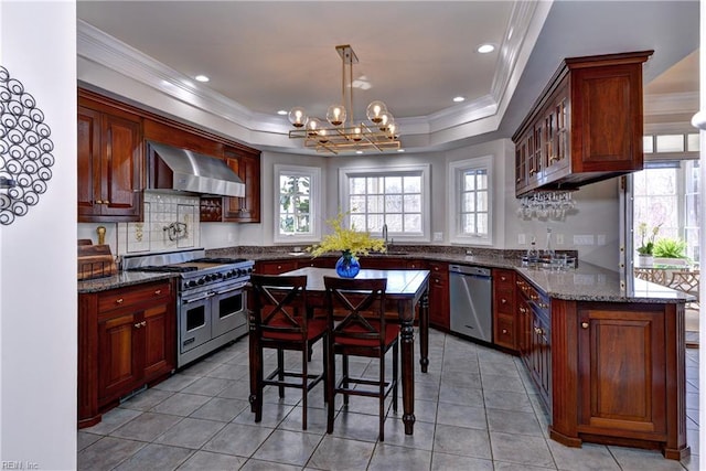 kitchen featuring a sink, stainless steel appliances, a healthy amount of sunlight, and wall chimney range hood