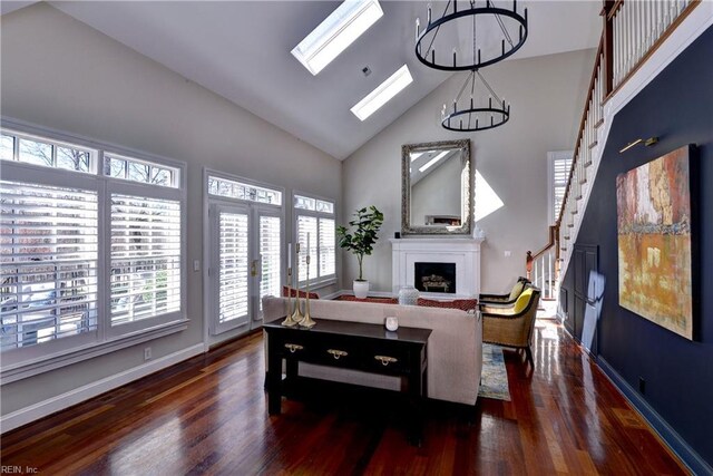 living room featuring high vaulted ceiling, wood finished floors, a skylight, a fireplace, and baseboards